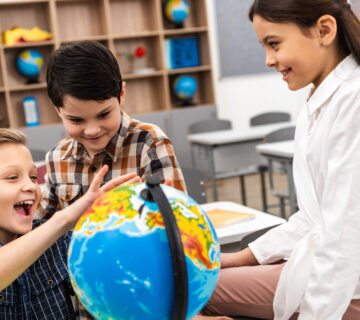 three-cheerful-pupils-playing-with-globe-in-class being bilingual