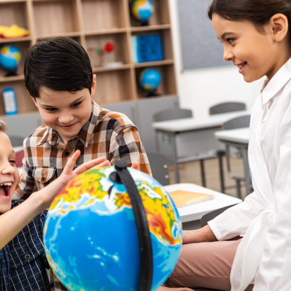 three-cheerful-pupils-playing-with-globe-in-class being bilingual